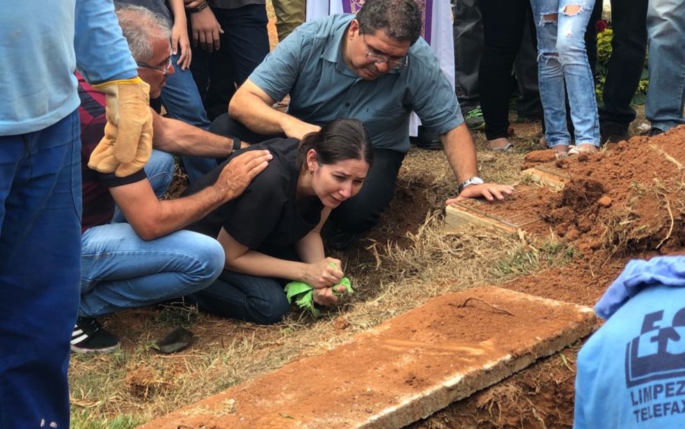 Mãe e pai (à direita) de João Vitor choram ao enterrar o corpo do filho