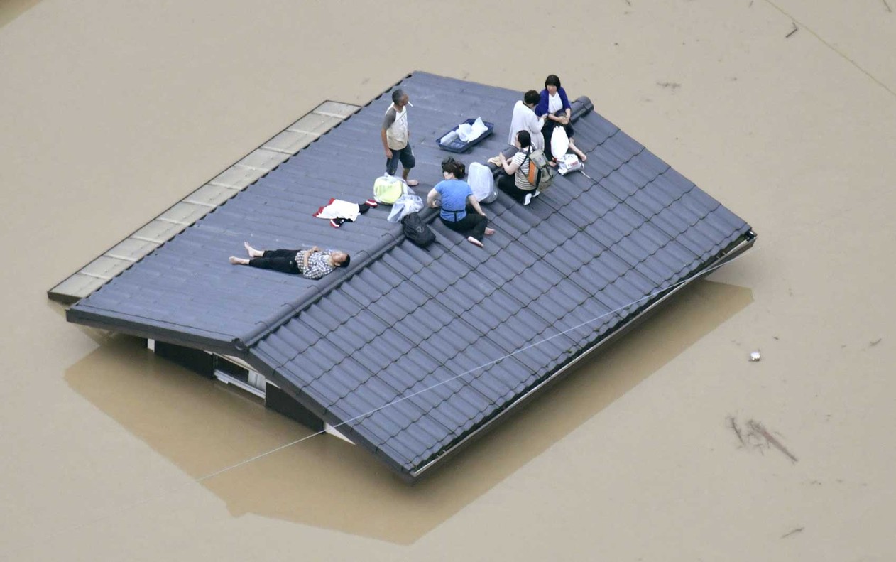 Vista aérea mostra moradores sobre telhado da casa submersa em uma área inundada em Kurashiki, sul do Japão