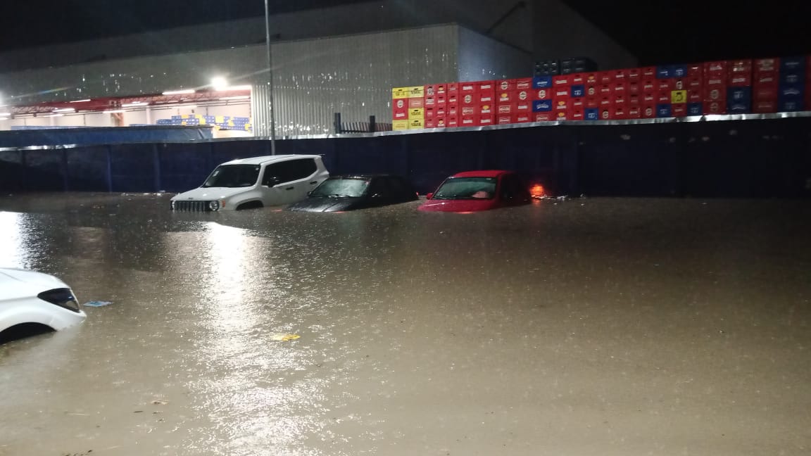 Carros cobertos pela água em estacionamento de supermercado em Teresina