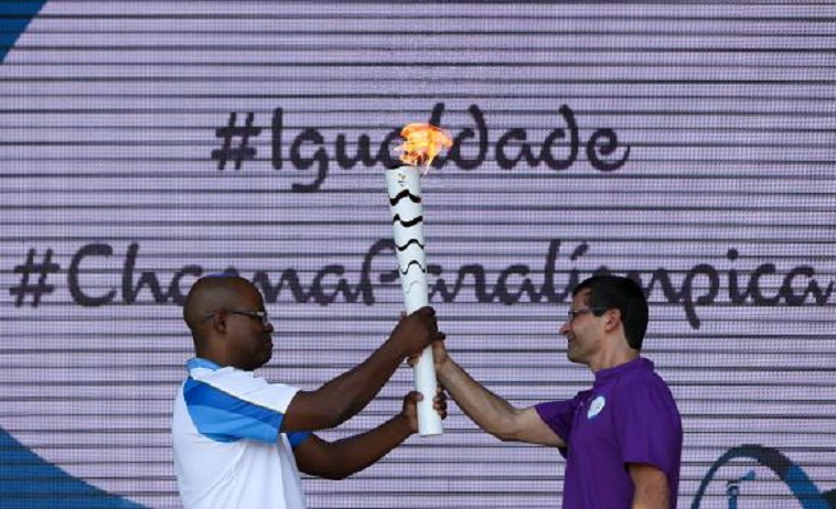 O mensageiro Ulisses de Araújo passa a tocha paralímpica para o tetracampeão de futebol de amputados, Cláudio Irineu