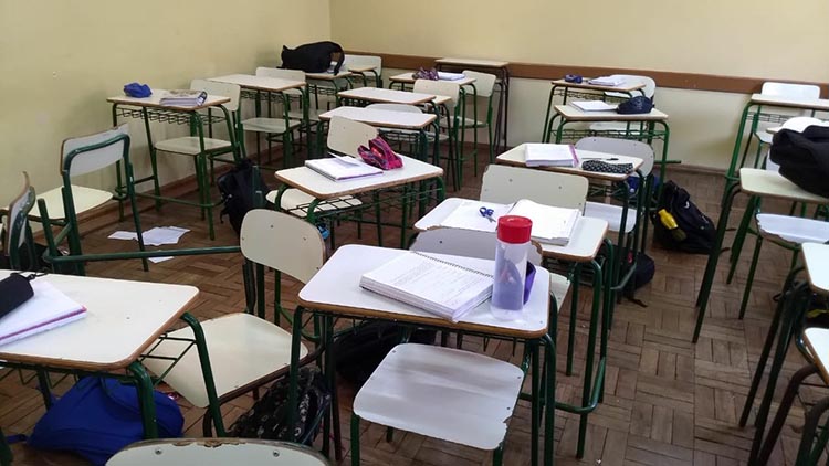 Na sala, as mochilas, cadernos e livros abandonados pelos alunos