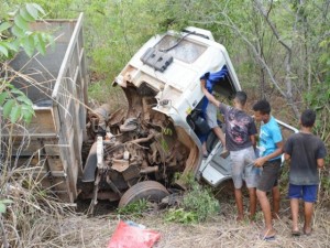 Curiosos observam o caminhão destruído dentro do mato na PI-255