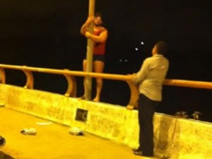 Jovem segura o porte da ponte e conversa com um homem