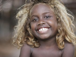 Criança de cabelos loiros e pela negra das Ilhas Salomão