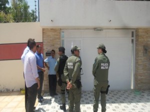 Policiais guardam a porta da residência onde ocorreu a tragédia