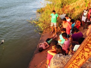 Curiosos observam corpo do atleta na margem do rio