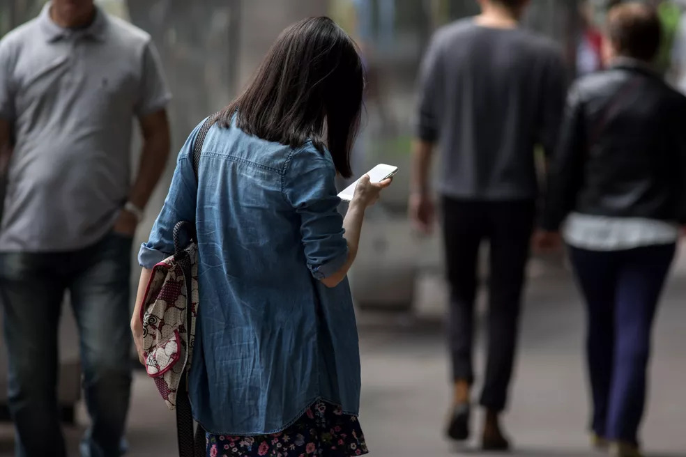 Mulher observa o celular na avenida Paulista, em São Paulo