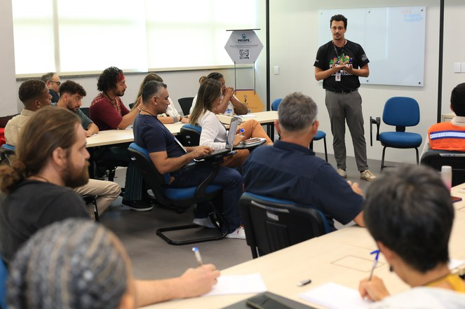 Na foto Leonardo Varallo disserta a frente de um quadro negro para pessoas em uma sala de aula