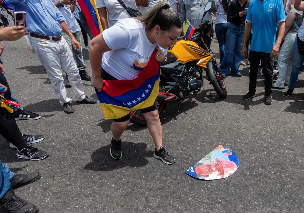 Mulher cospe em foto de Maduro em protesto em Maracaibo, na Venezuela