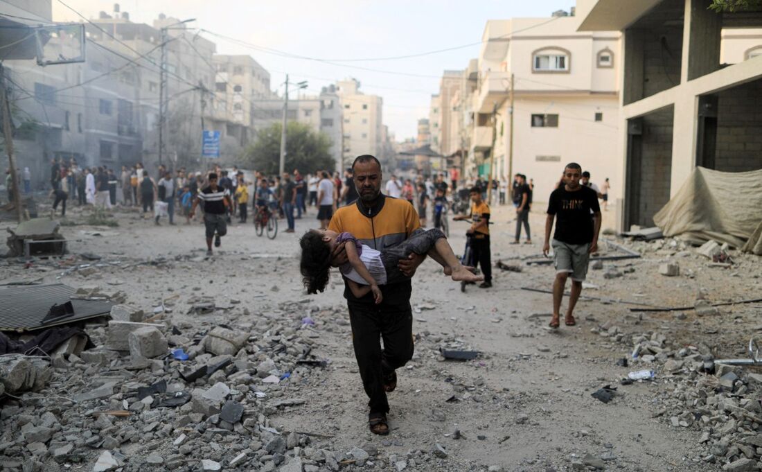 Criança sendo carregada no colo após ataque na Faixa de Gaza