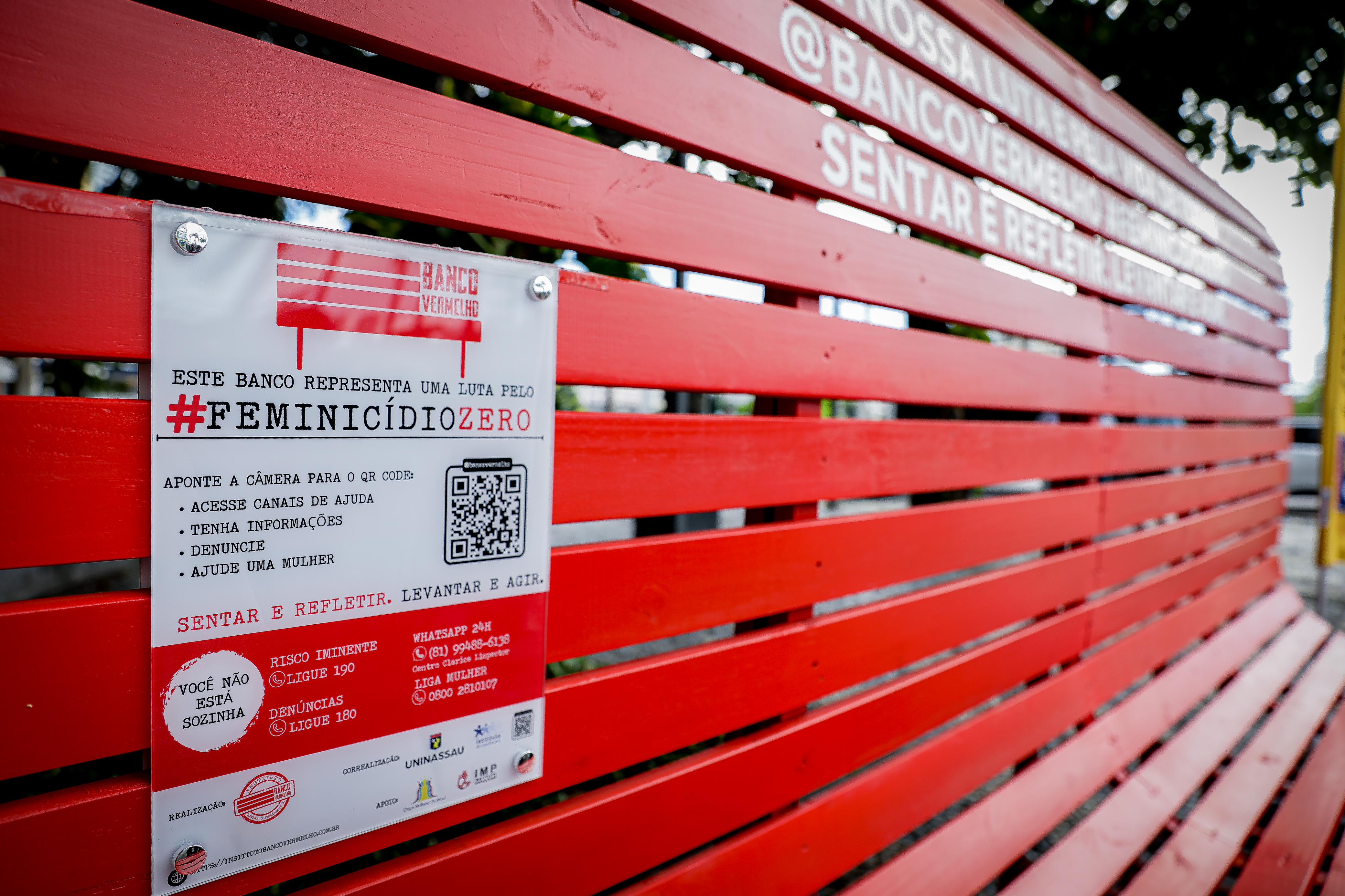 O banco vermelho gigante tem frases de conscientização e números de canais de denúncia de violência contra a mulher