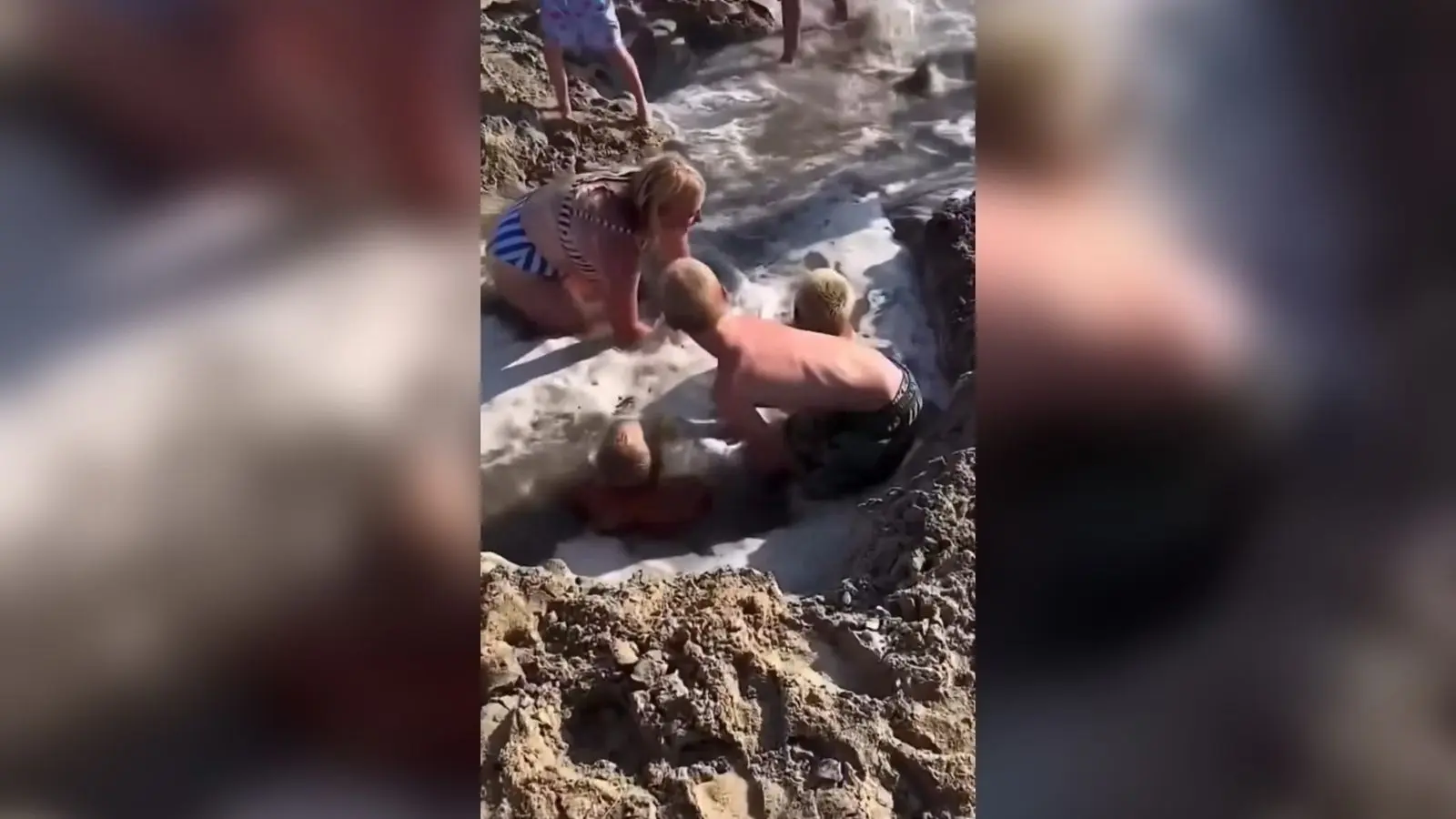 Crianças ficam presas em buraco de areia após chegada de onda