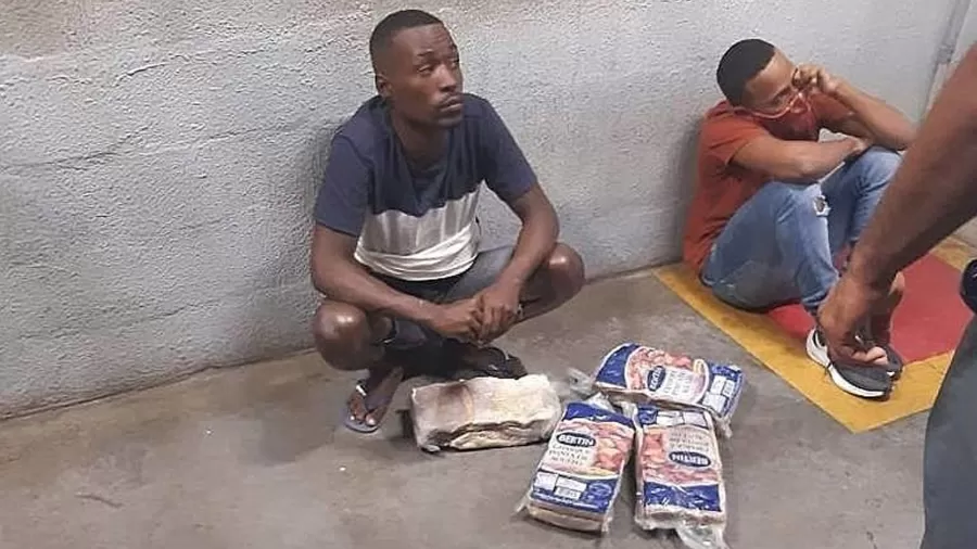 Bruno e Yan sentados no pátio do supermercado ao lado dos quatro pacotes de carne no Atakarejo