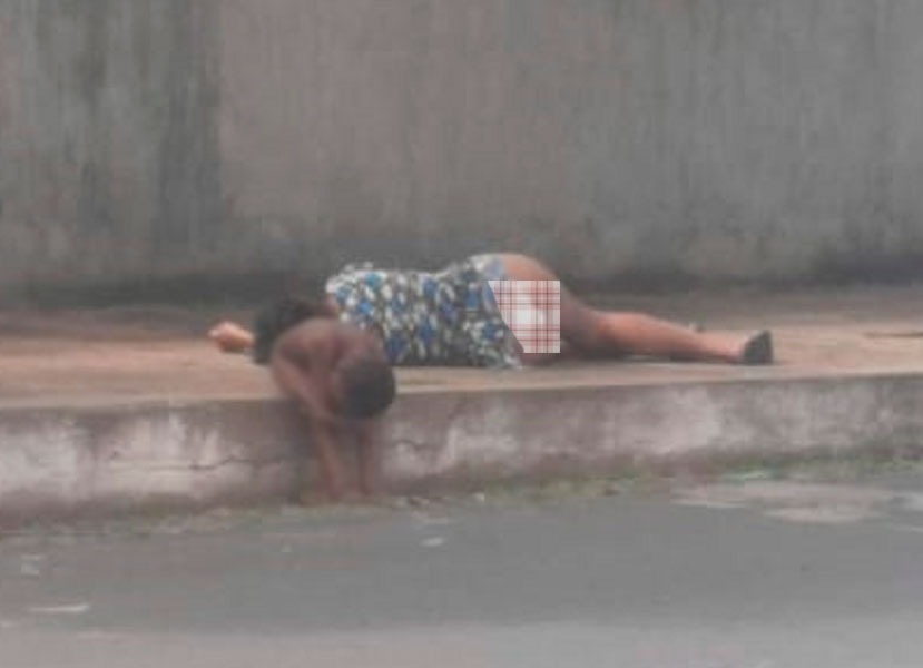 Criança na calçada enquanto a mãe dorme embriagada