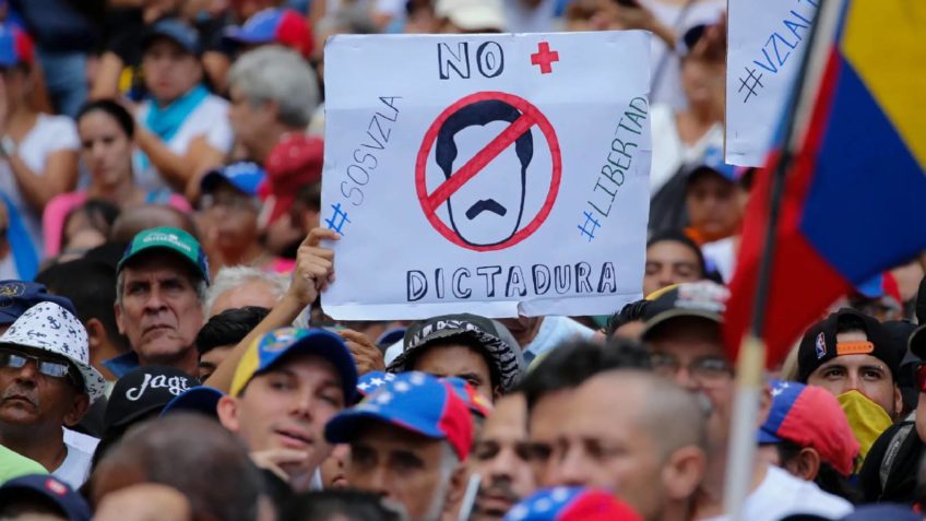 Manifestante segura cartaz com os dizeres: “não mais ditadura”, “SOS Venezuela” e “liberdade”