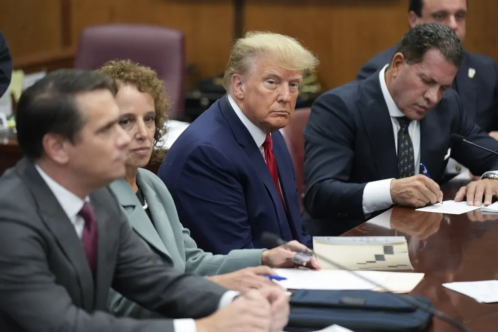 O ex-presidente Donald Trump senta-se à mesa da defesa com sua equipe no Tribunal Criminal de Manhattan, Nova York, EUA, em 4 de abril de 2023