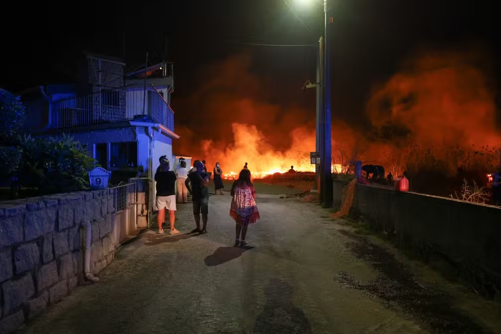 Moradores do povoado de Canas de Senhorim, perto de Viseu, no centro de Portugal, observam chamas que se aproximam das casas, em 16 de setembro de 2024