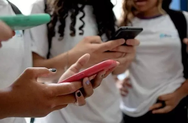 Adolescentes usam celulares na escola