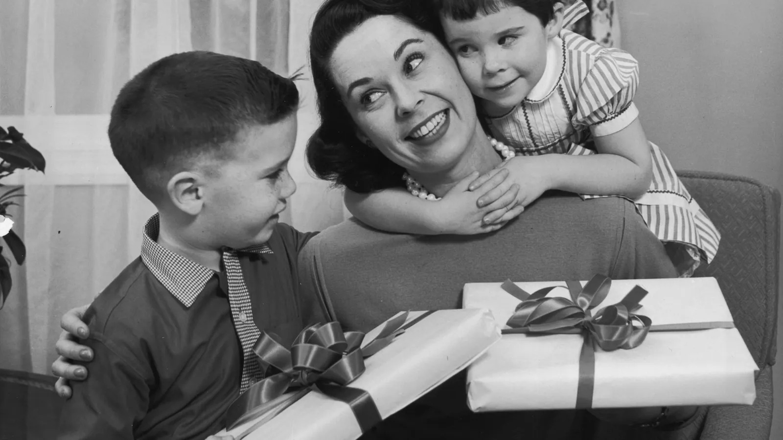 Um menino e uma menina dão presentes para a mãe deles no Dia das Mães na década de 1950, nos Estados Unidos